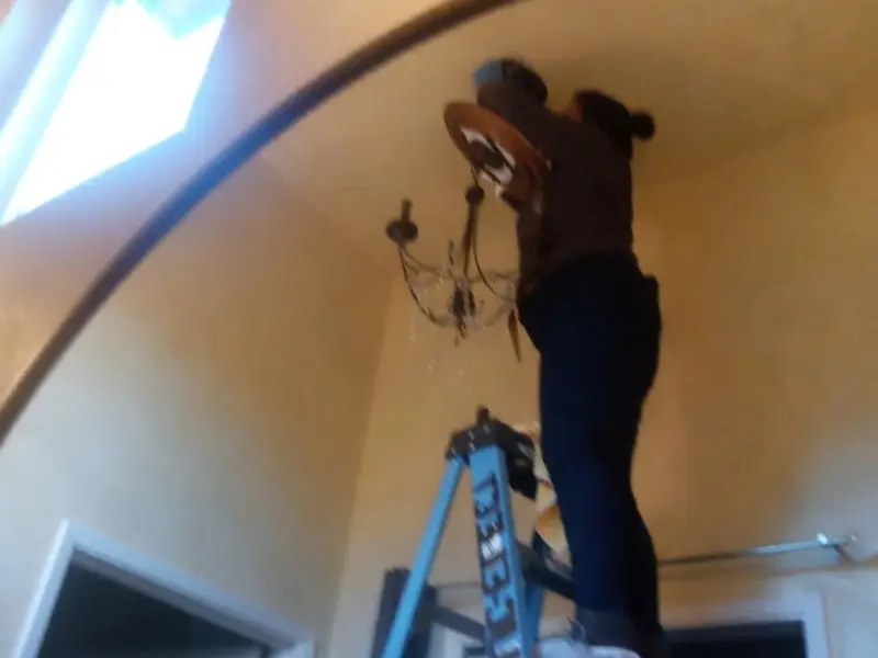 Electrician installing a chandelier in a Newport residence